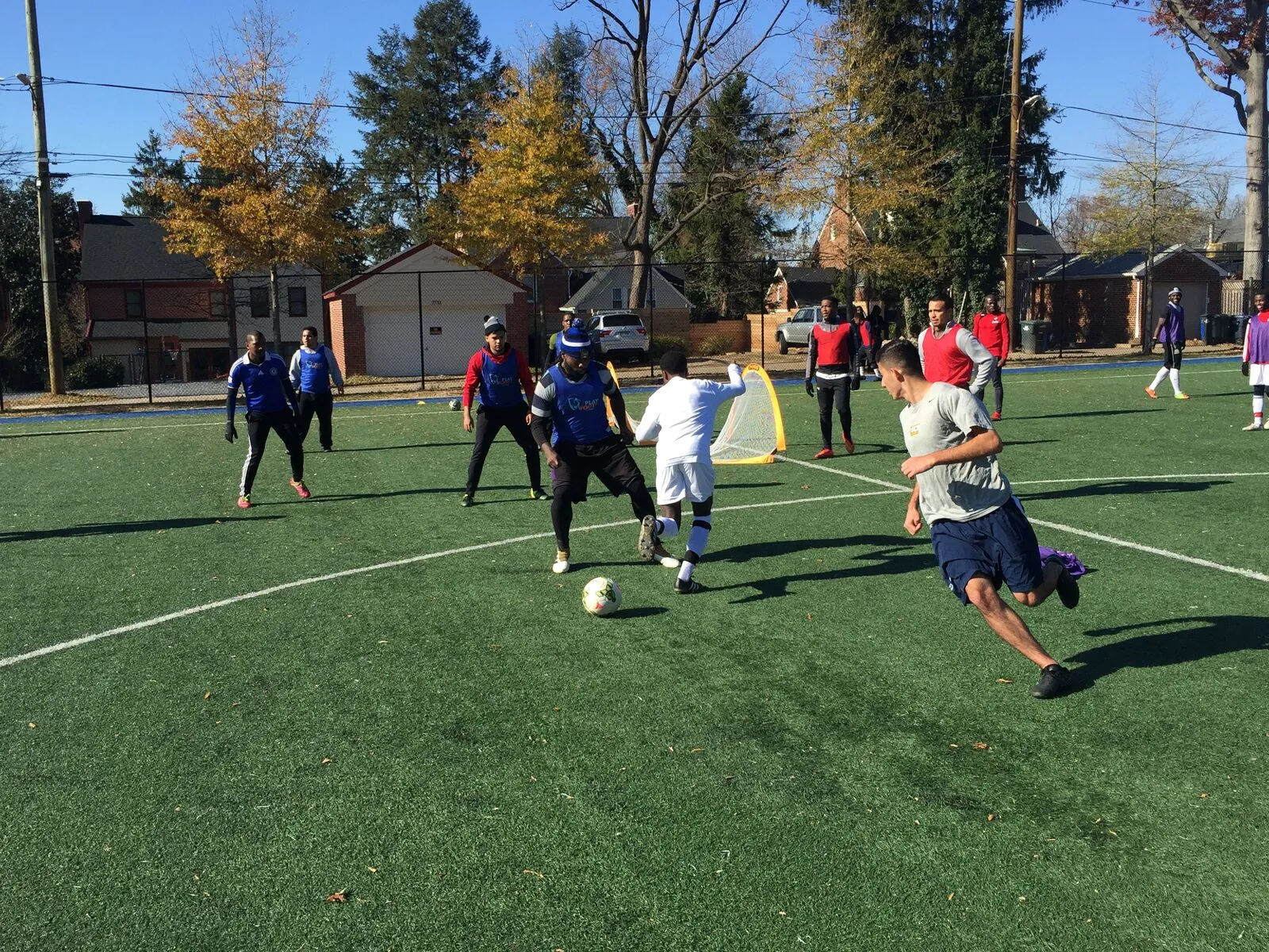 2017: A young player in white and an adult in grey chase the ball in a mixed-age game.