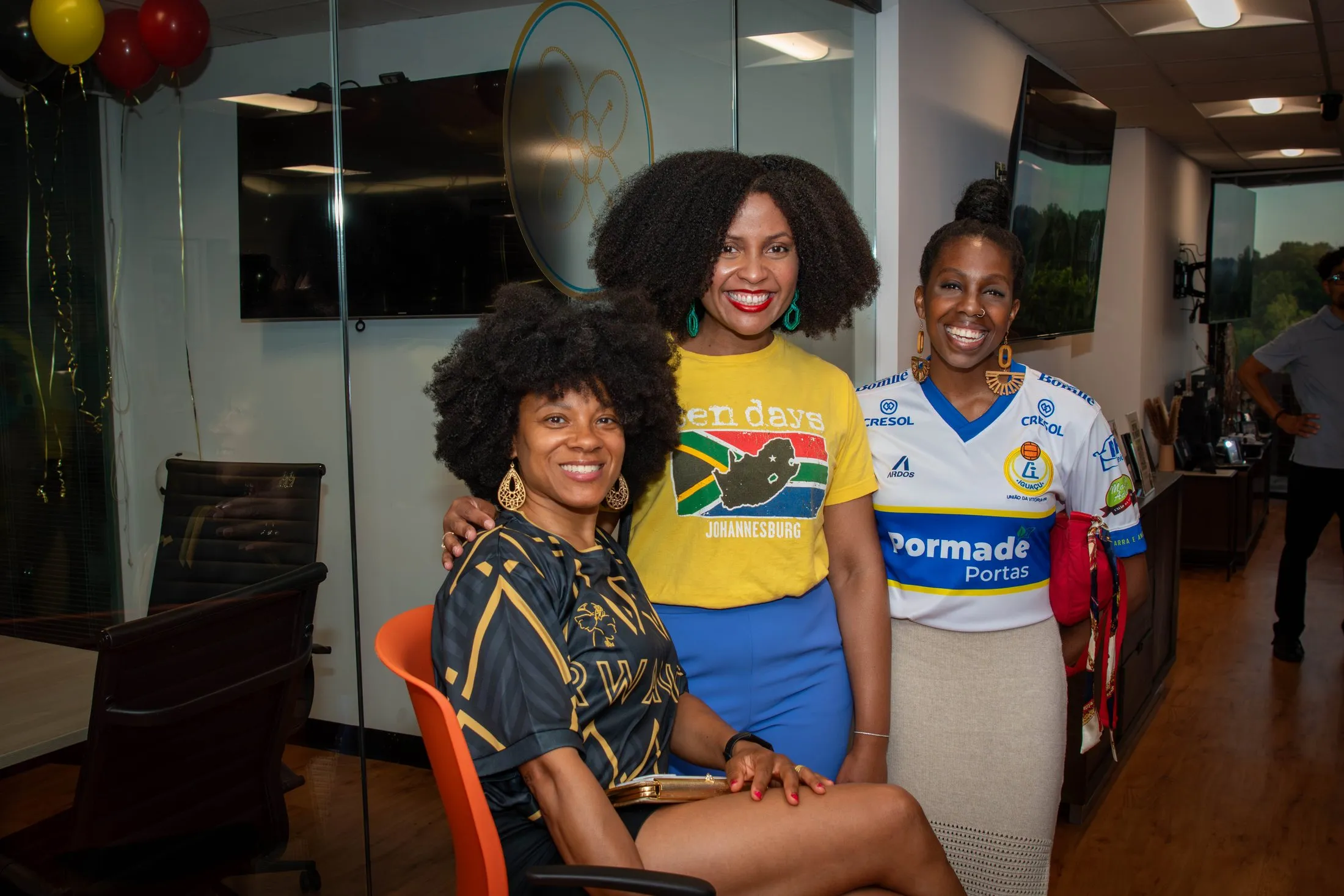 Three women in football jerseys from different countries smile together at the gala.