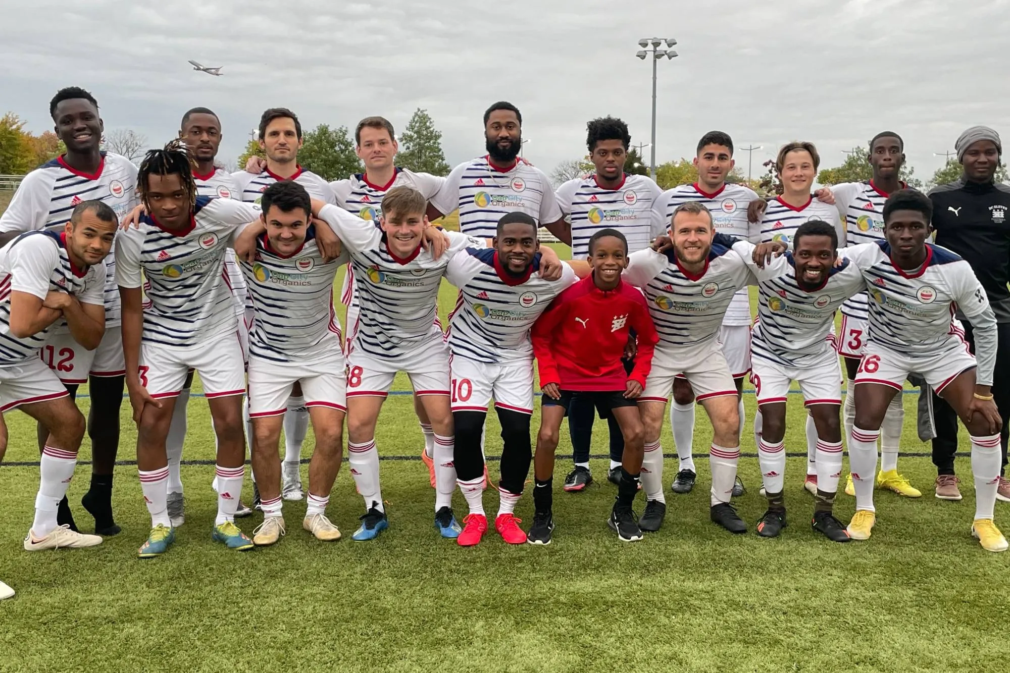 The DCXI Pro men's team poses together on a turf field in white striped kits.