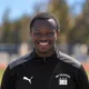 Coach Jean-Marie Gnambode, smiling, wearing a black DC Eleven training jacket